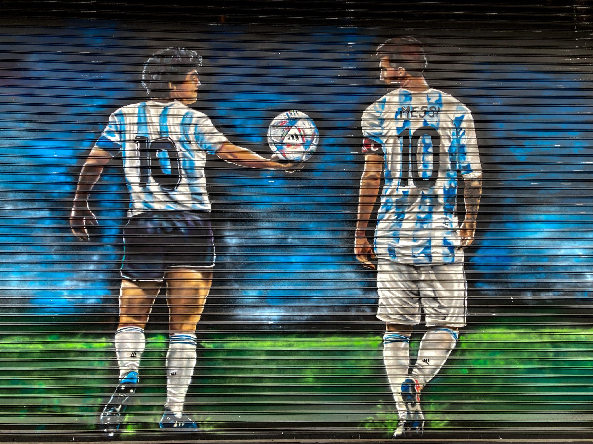street art in Buenos Aires depicting football stars Diego Maradona and Lionel Messi in argentina national soccer team jersey